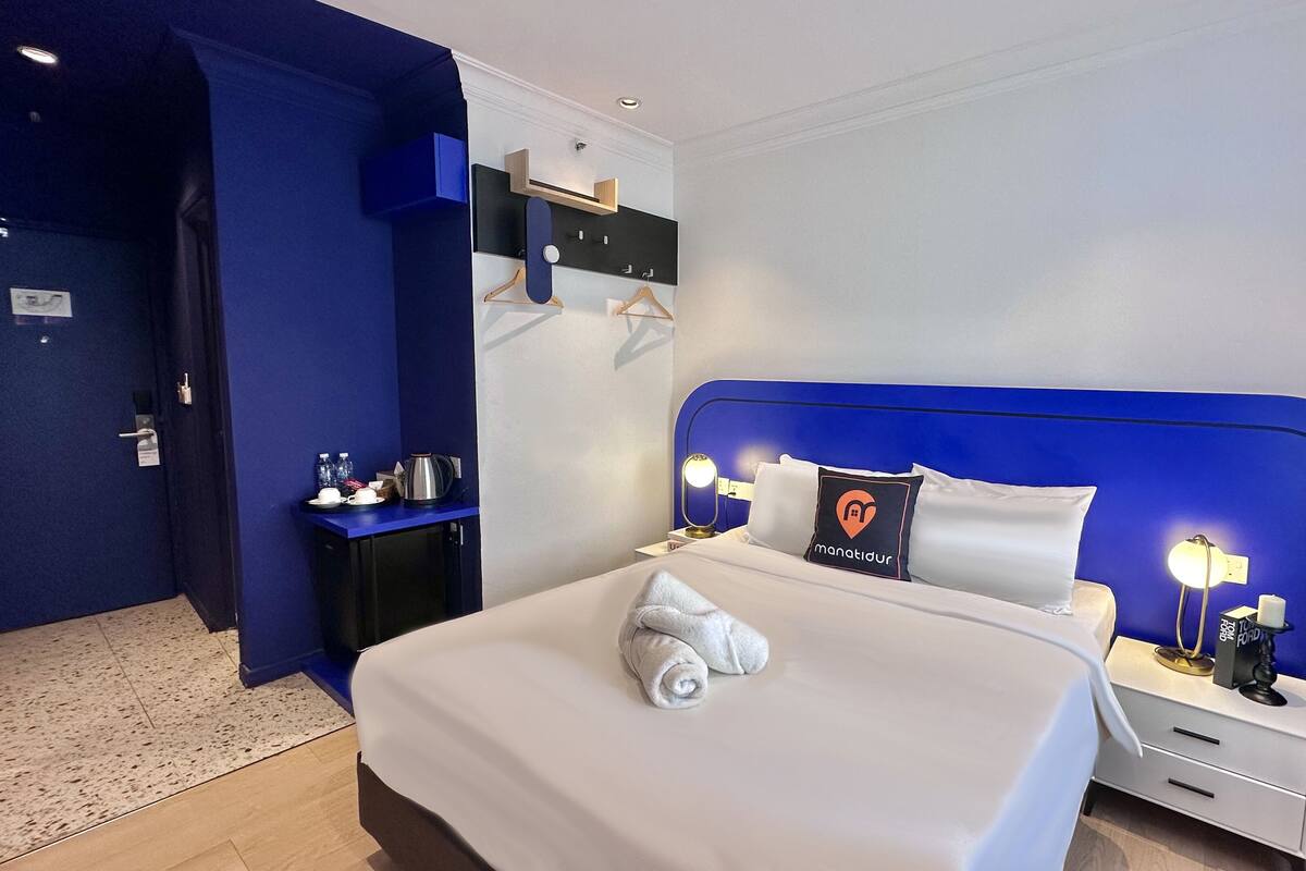 Ein modernes Hotelzimmer mit einem großen Bett, Nachttischen und einem blauen Kopfteil.