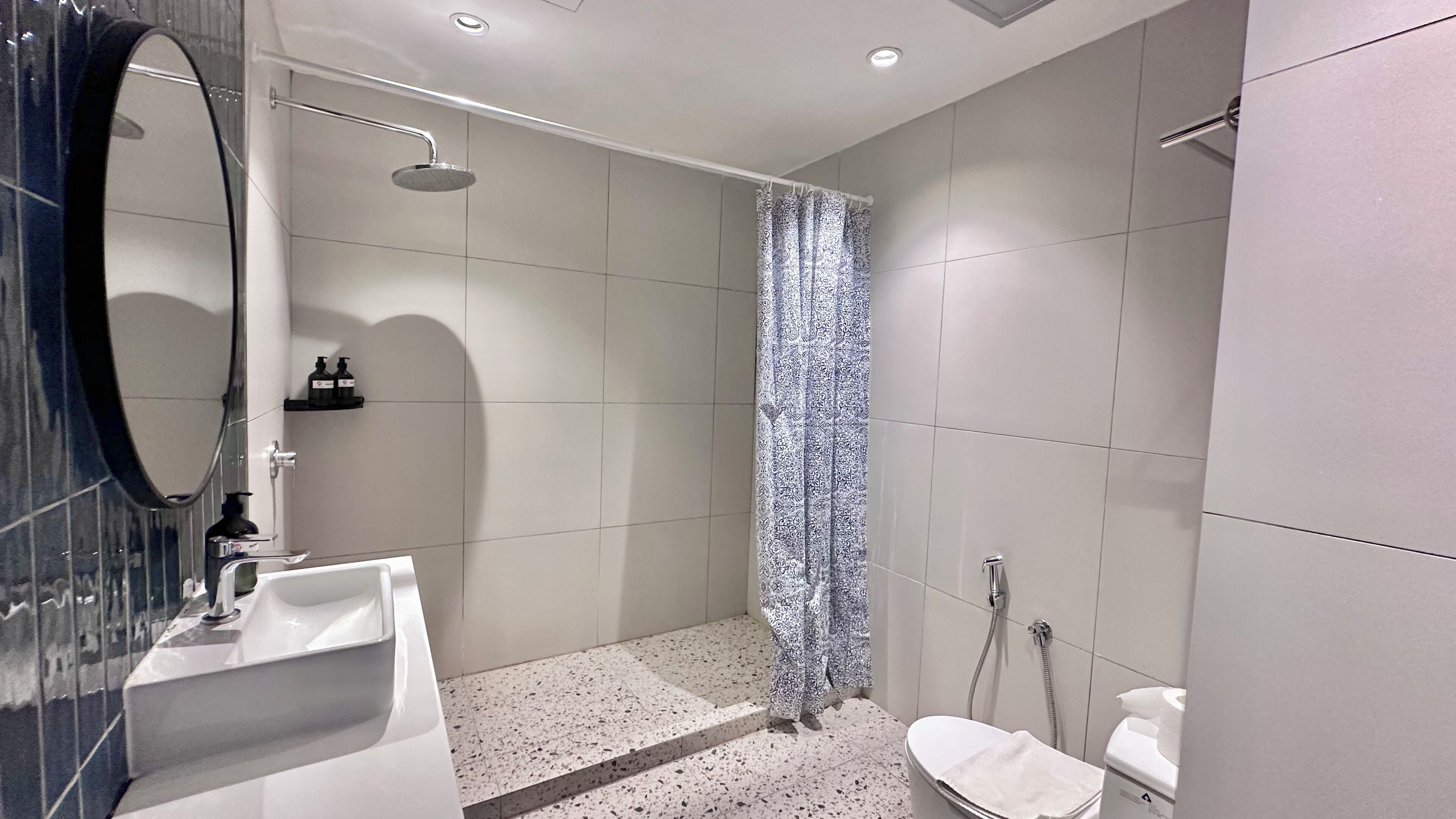 A modern bathroom with a shower, toilet, and sink.