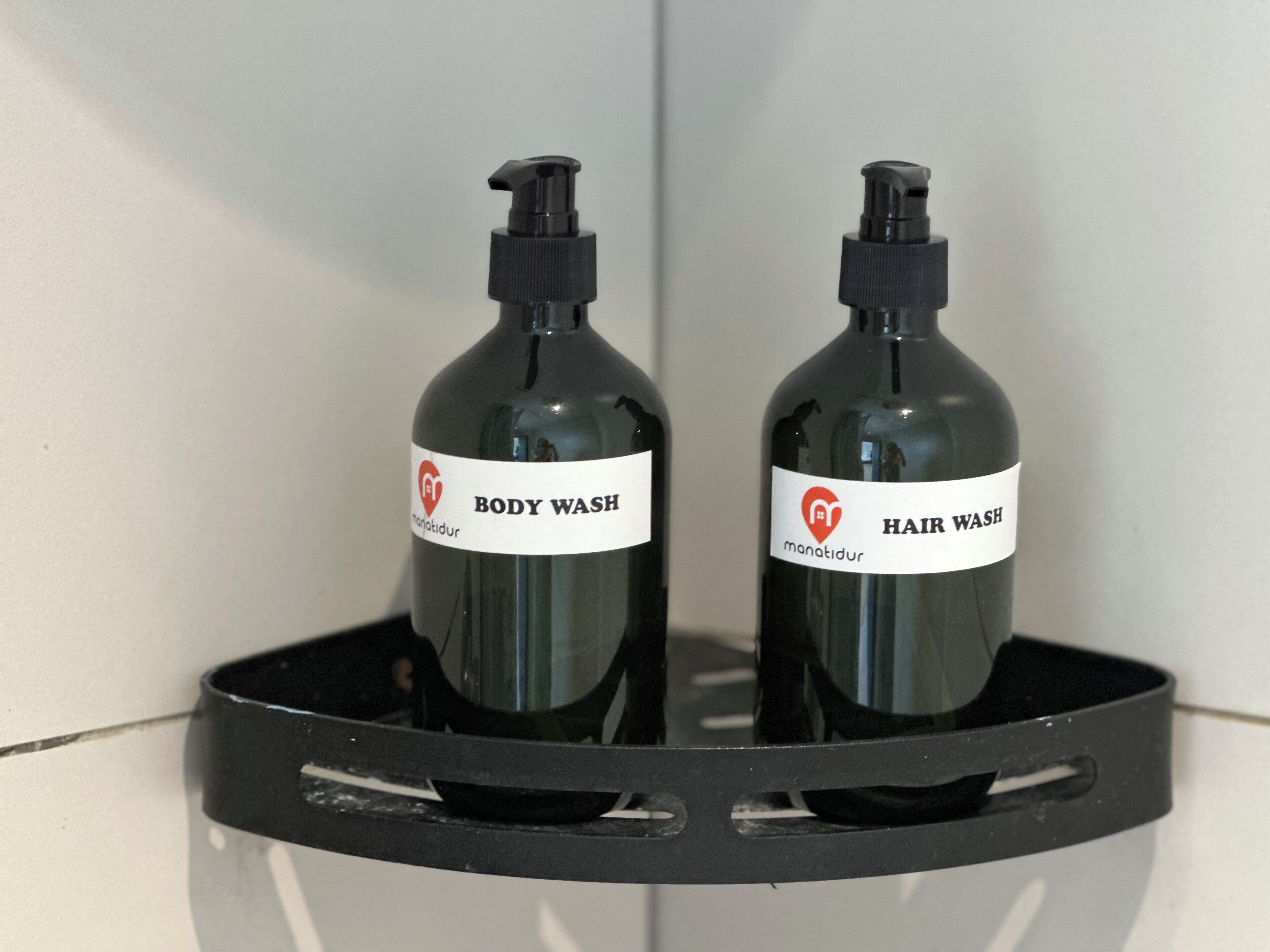Two bottles of body wash and hair wash on a black shelf.