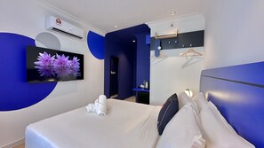 Une chambre d’hôtel moderne équipée d’un lit, d’une télévision à écran plat, d’un bureau avec une bouilloire et d’une armoire.