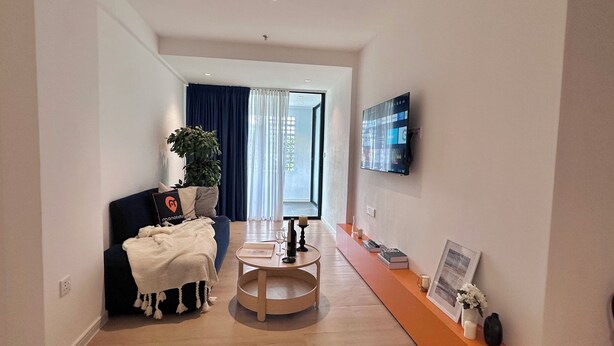 Uma sala de estar moderna com um sofá, mesa de centro e uma TV de tela plana na parede.