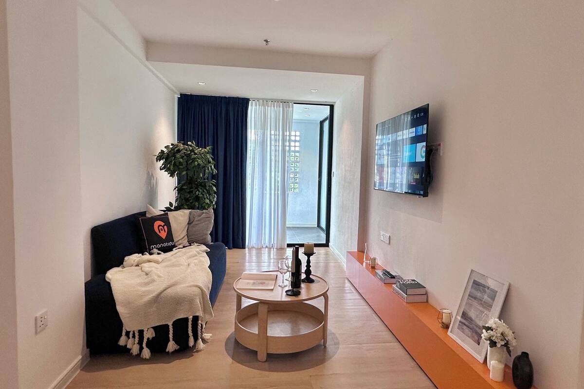 Ein modernes Wohnzimmer mit einer Couch, einem Couchtisch und einem an der Wand befestigten Flachbildfernseher.