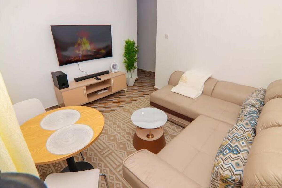 A living room with a sofa, a coffee table, a TV, and a small table with a plant.