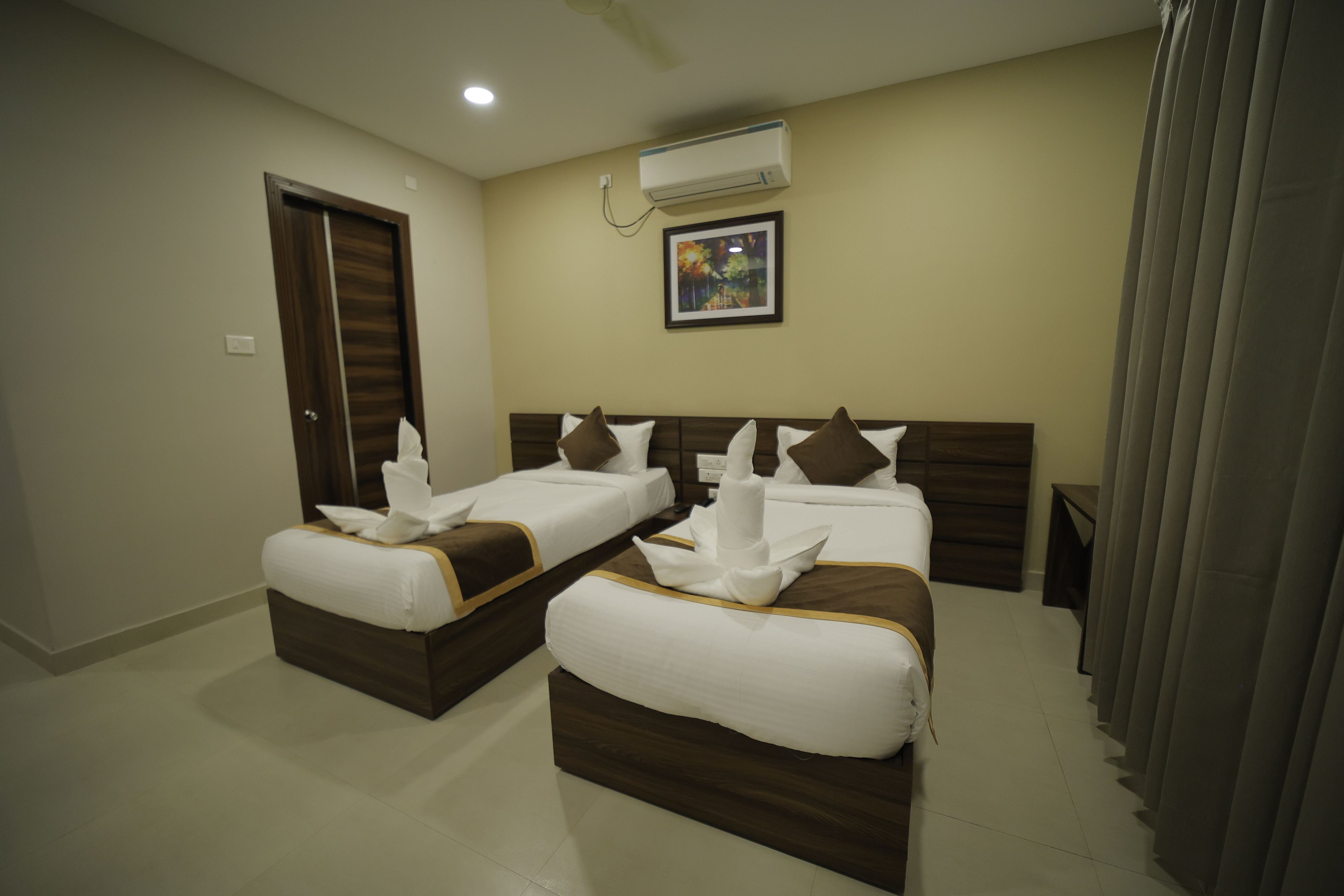 Habitación de hotel con dos camas, una puerta, un equipo de aire acondicionado y un cuadro en la pared.