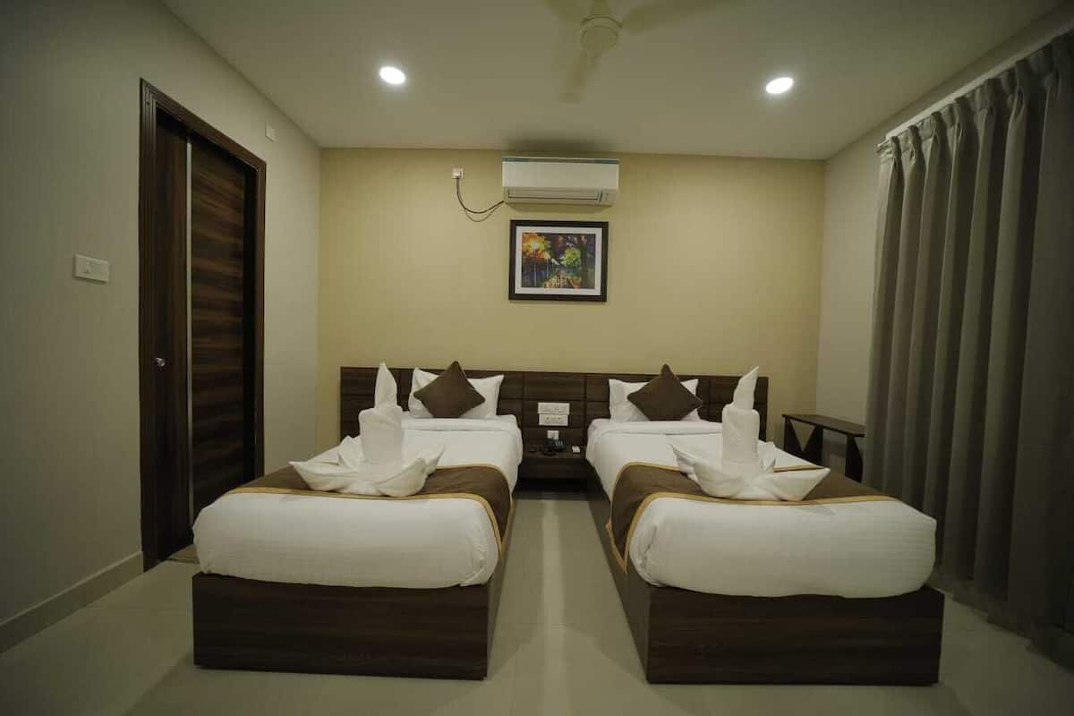 A hotel room with two beds, a ceiling fan, an air conditioning unit, and a framed picture on the wall.