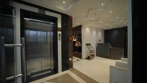 Un hall d’entrée moderne avec un comptoir d’accueil, un escalier et un ascenseur.