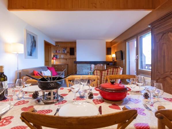 A dining area with a table set for four, a red pot, wine glasses, and a candle holder.