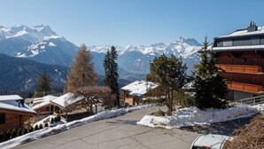 A mountain resort with snow-covered buildings, a clear view of snow-capped mountains, and a paved road. - Richemont 8C by Interhome (Villars)