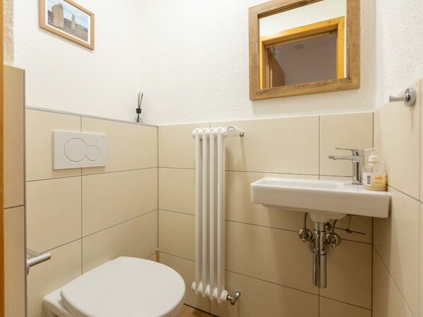 Une petite salle de bain moderne, équipée d’un WC, d’un lavabo et d’un radiateur.
