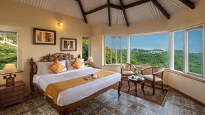 A spacious bedroom with a large bed, a view of the countryside, and a cozy seating area. - Teanest Nightingale - Nature Resorts (Kotagiri)