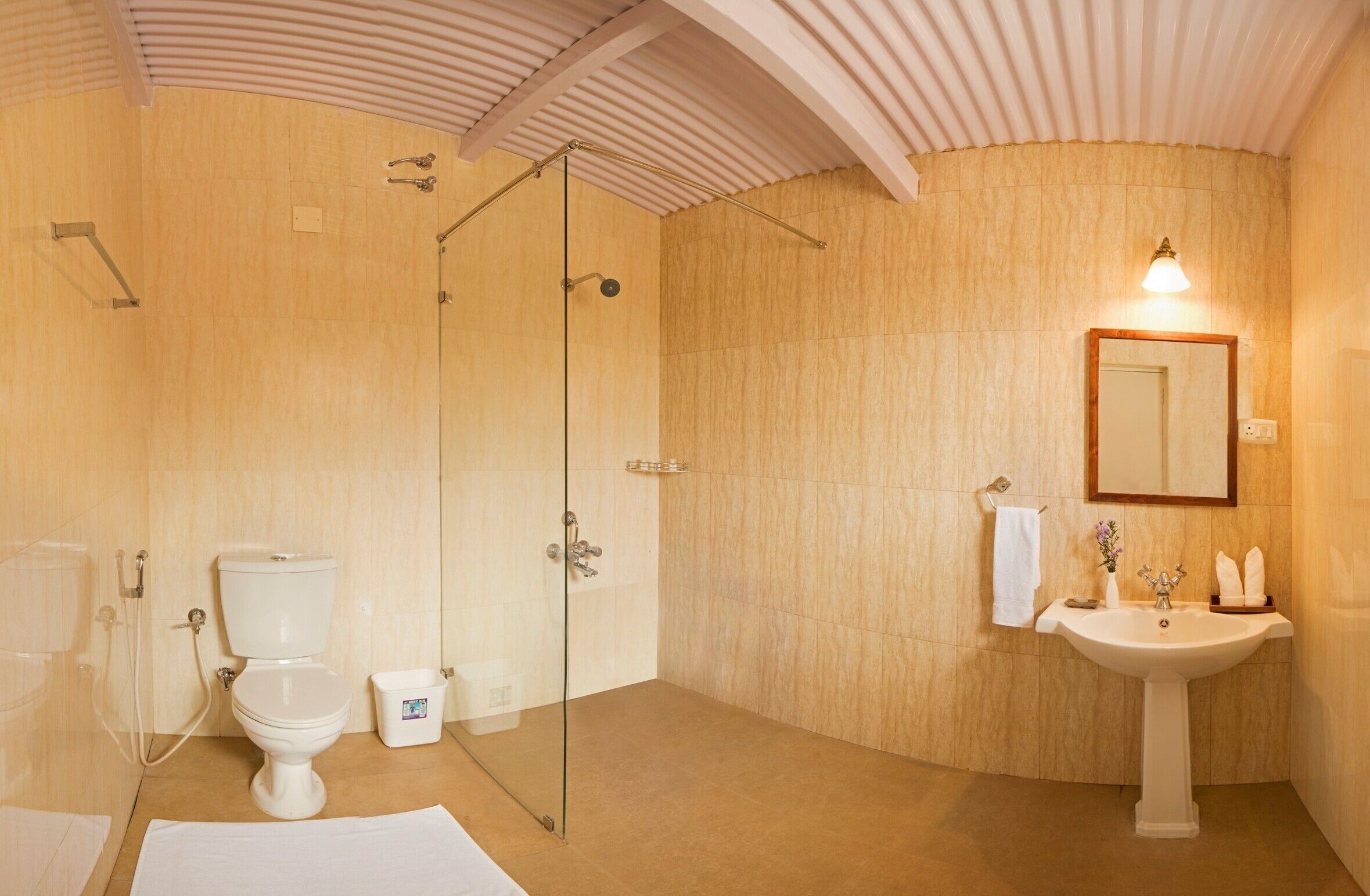 A bathroom with a glass-enclosed shower, a toilet, and a sink with a mirror above it.