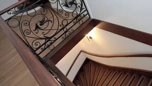 A wooden staircase with a curved handrail and a decorative metal railing with a bird design.