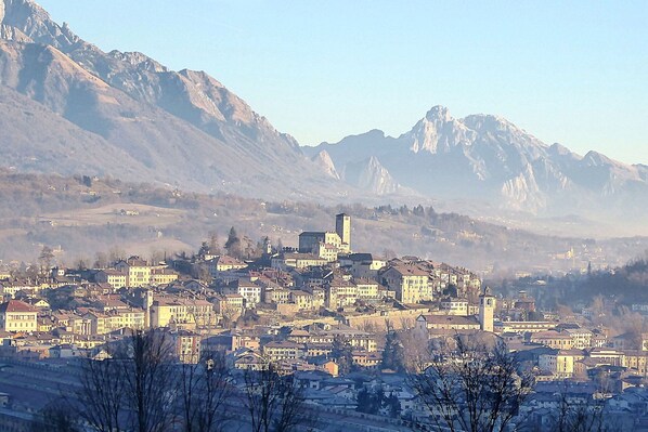 A town with historic buildings, a prominent tower, and mountains in the background.