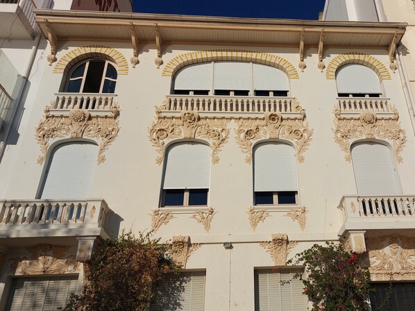 Um edifício com detalhes arquitetônicos elaborados, incluindo sacadas decorativas e janelas em arco.