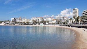 Un hôtel situé en bord de mer, avec plusieurs étages, une plage de sable et une mer d’un bleu limpide.