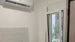 A modern kitchen with a white tiled backsplash, a bar area with two black bar stools, a stainless steel sink, and a red fire extinguisher. - Central Studio next to Metro (Pireaus)