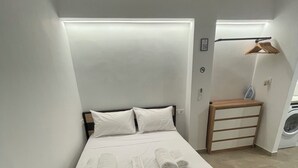 A modern bedroom with a bed, pillows, and neatly folded towels. - Central Studio next to Metro (Pireaus)