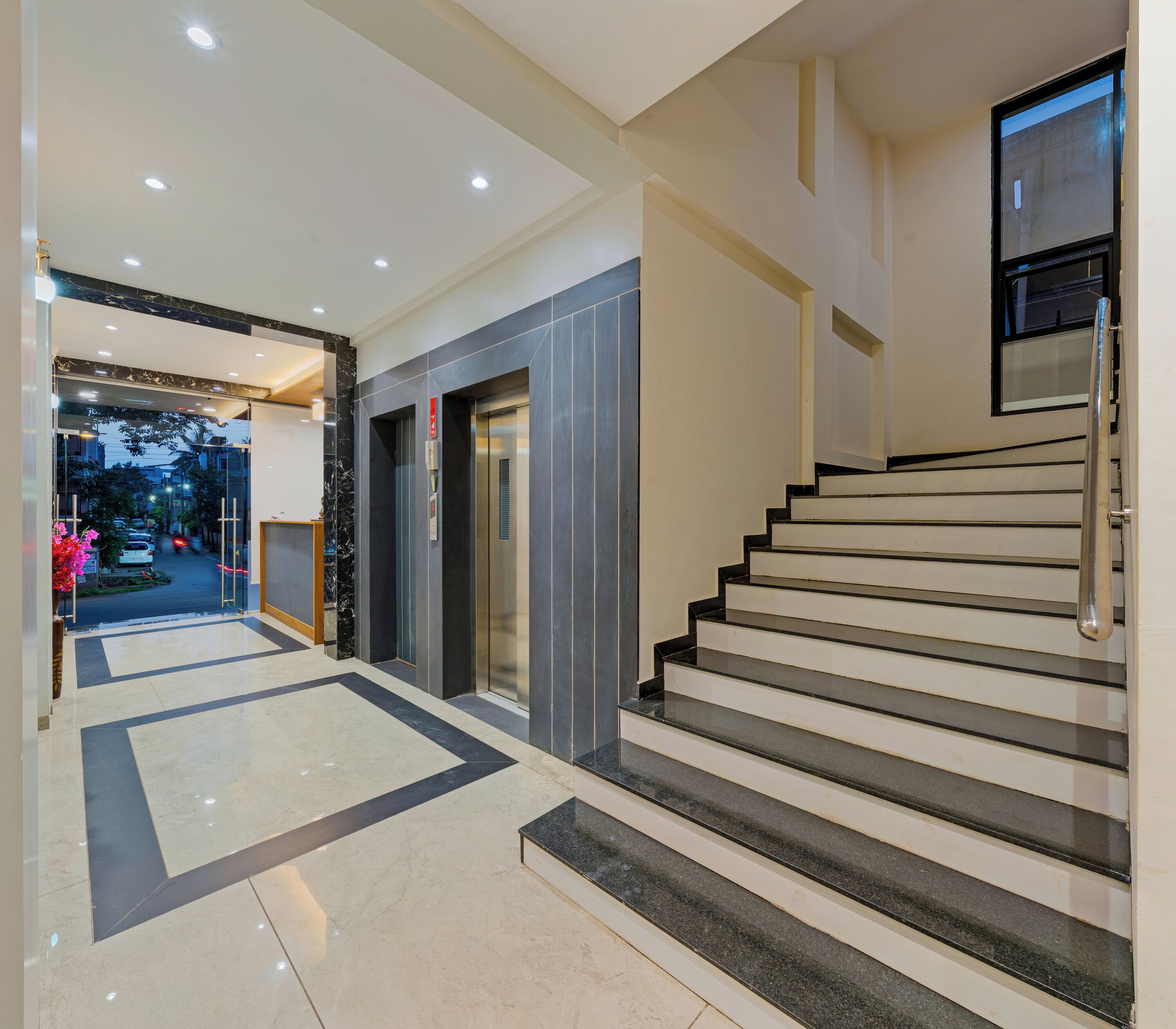 Una hall d'hotel moderna con pavimento in marmo, una scala e un ascensore.