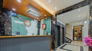A hotel reception area with a marble reception desk, a wooden ceiling, and a staircase leading to the upper floor. - Hotel The Container (Kolhapur)