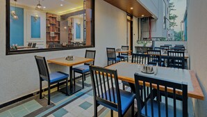 A restaurant with outdoor seating, a large mirror reflecting the interior, and a view of the cityscape. - Hotel The Container (Kolhapur)