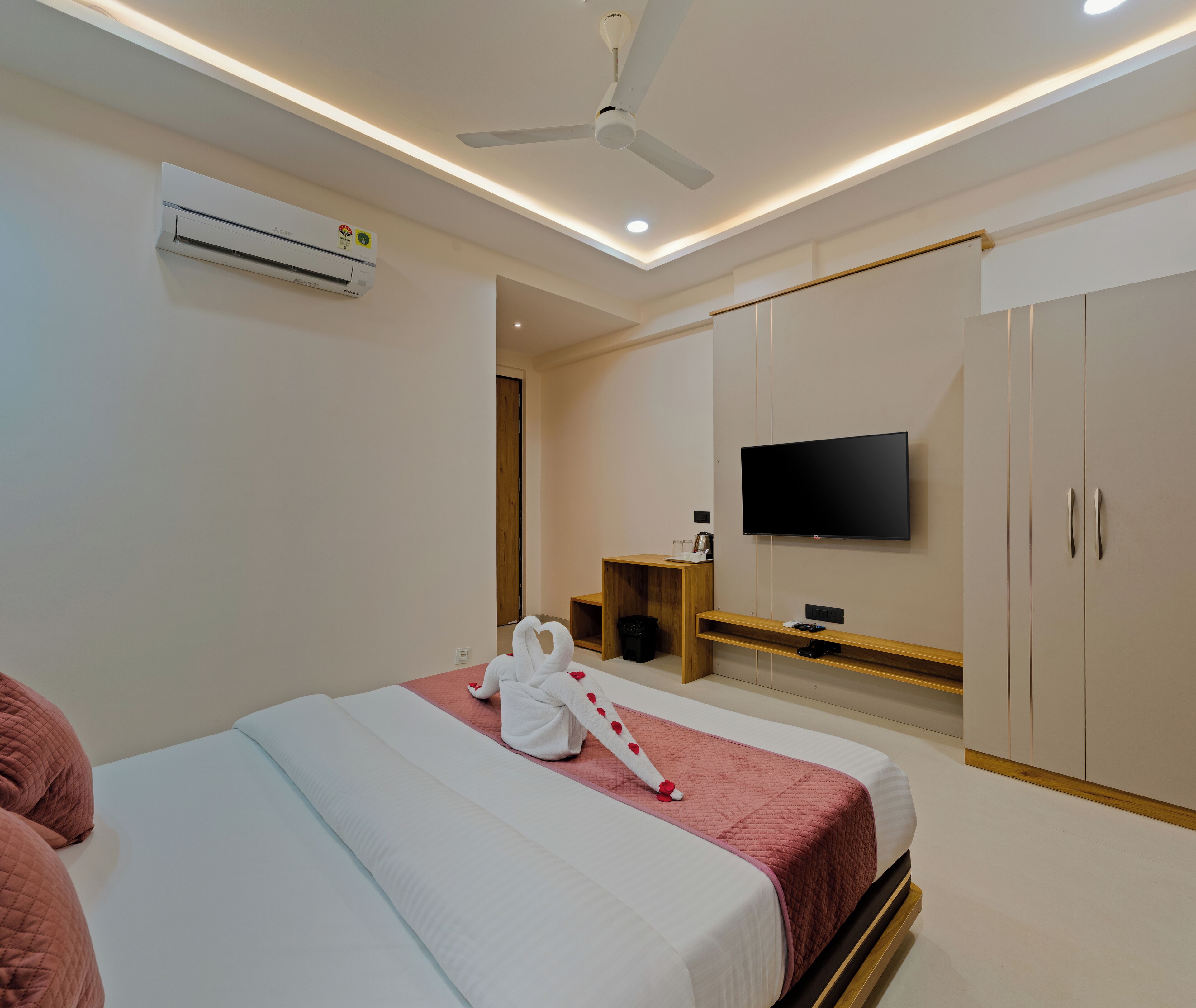 Camera d'albergo moderna con un letto, una televisione a schermo piatto montata a parete, una ventola a soffitto e un armadio.