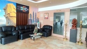 A modern lobby with a black leather sofa, a glass coffee table, and a cityscape mural. - JB Residency (Tiruchirappalli)