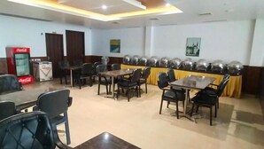 A conference room with tables and chairs, a Coca-Cola refrigerator, and a reserved sign on the table. - JB Residency (Tiruchirappalli)