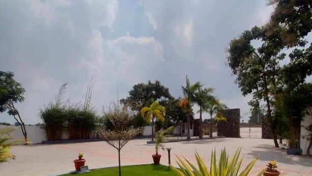A well-maintained outdoor area with a lawn, potted plants, and a paved walkway. - JB Residency (Tiruchirappalli)