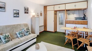 A compact living space with a sofa, a dining table with chairs, a kitchenette, and a small refrigerator. - Apartment Residence at the foot of the slopes "Zen Altitude" 6 people (Eaux-Bonnes)