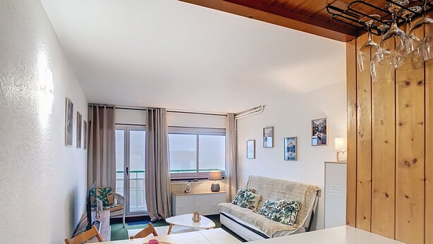 A cozy living room with a sofa, a dining table, and a view of the outdoors. - Apartment Residence at the foot of the slopes "Zen Altitude" 6 people (Eaux-Bonnes)