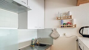 A compact kitchen with a gas stove, two sinks, and wooden shelves above the countertop. - Apartment Residence at the foot of the slopes "Zen Altitude" 6 people (Eaux-Bonnes)