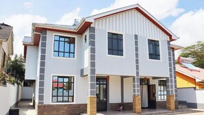 A two-story house with a front porch, large windows, and a garage. - Lux Suites Advent Homes Naivasha (Naivasha)
