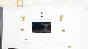 A modern living room with a flat-screen TV mounted on a white wall, surrounded by potted plants. - Lux Suites Advent Homes Naivasha (Naivasha)