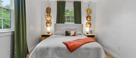 Ein modernes Schlafzimmer mit einem großen Bett, grünen Vorhängen und dekorativen Wandleuchten.