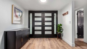 A hallway with a black door, a radiator, a potted plant, and a framed picture on the wall. - NEW|The Bungalow @ Old Town|Al-Fresco Living|Pool (Scottsdale)