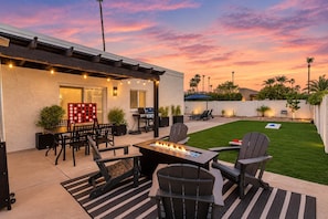 A patio with a fire pit, outdoor furniture, and a view of the backyard.