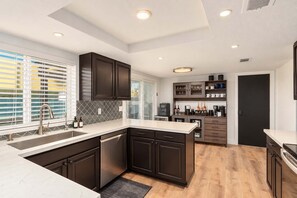 A modern kitchen with dark cabinetry, a white countertop, and built-in appliances.