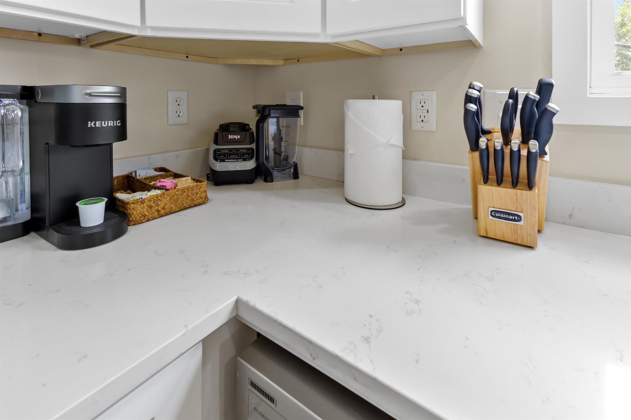 Ett kök med en kaffemaskin från Keurig, en matberedare från Ninja och ett knivblock från Cuisinart.