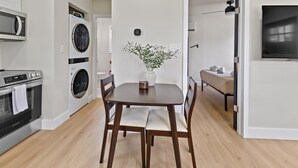 Eine moderne Küche mit Einbauofen, Mikrowelle und Waschmaschine. Ein Esstisch mit Stühlen und eine Wandvase mit Blumen sind vorhanden.