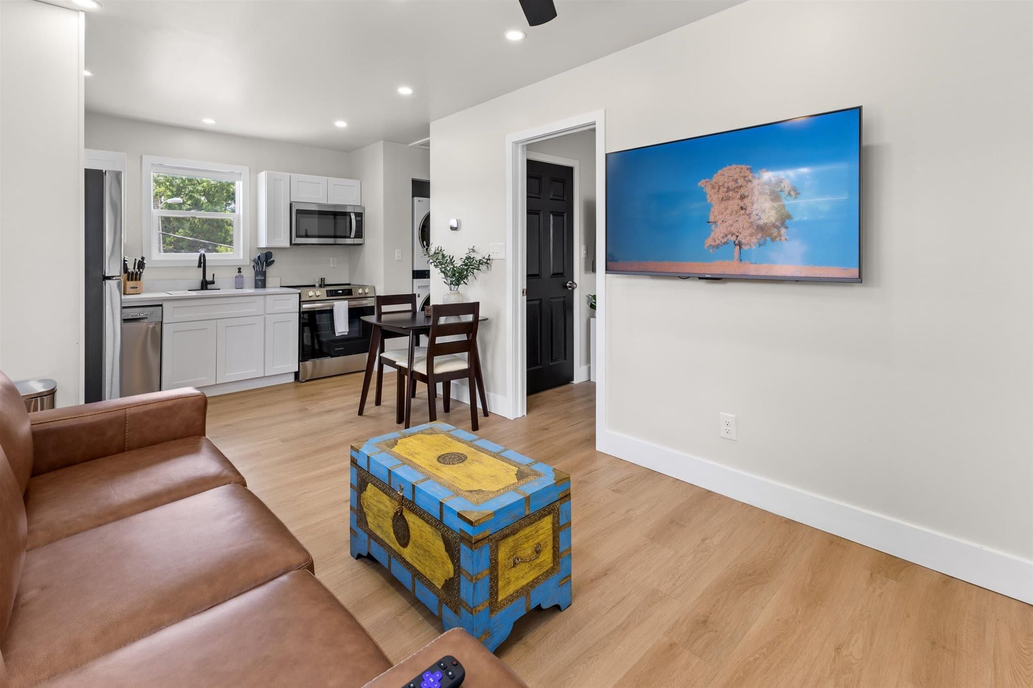 Un salon moderne avec un canapé en cuir marron, une table basse en bois et un téléviseur à écran plat fixé au mur.
