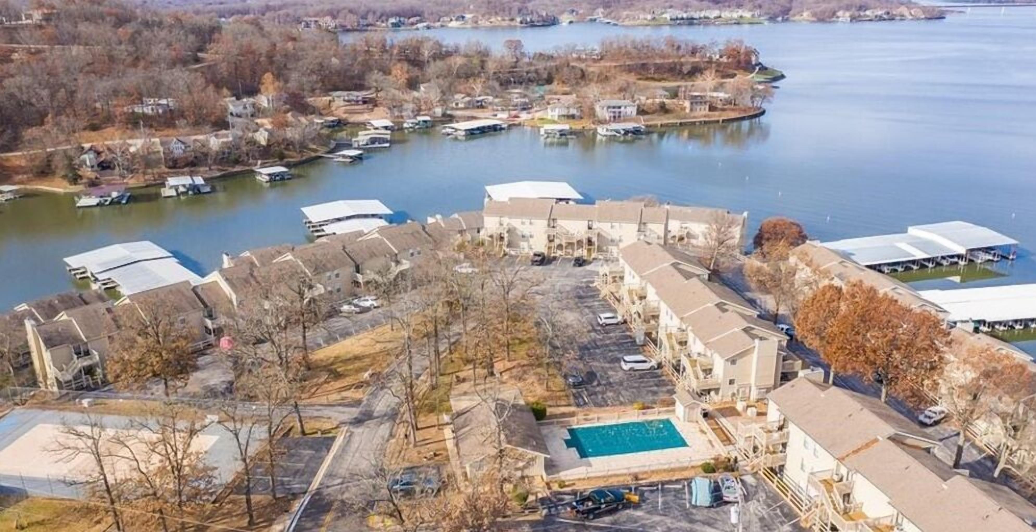 Vista aérea de uma área residencial com uma grande piscina, vários barcos na água e diversos tipos de casas e edifícios.