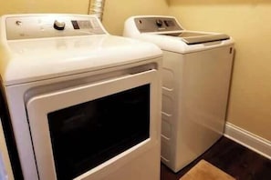 A laundry room with two white washing machines and a dryer.