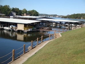 A marina with docked boats, covered structures, and a grassy area.