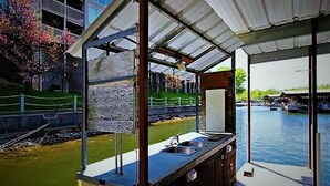 Une cuisine extérieure abritée, avec vue sur une rivière et un bâtiment en arrière-plan.