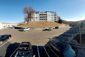 A parking lot with several cars and a multi-story building in the background.