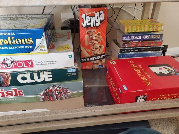 A shelf with various board games including Monopoly, Clue, and Jenga.