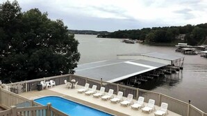 Une piscine dotée de chaises longues et d’une terrasse offrant une vue sur une étendue d’eau avec des quais.