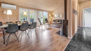 Amplia habitación con techo de madera, chimenea y comedor con sillas y mesa.