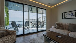 A modern living room with a sofa, a coffee table, and a view through large sliding glass doors to an outdoor patio with chairs and a table. - Wow!  Where Dreams become Reality! New Luxury Unit (Osage Beach)