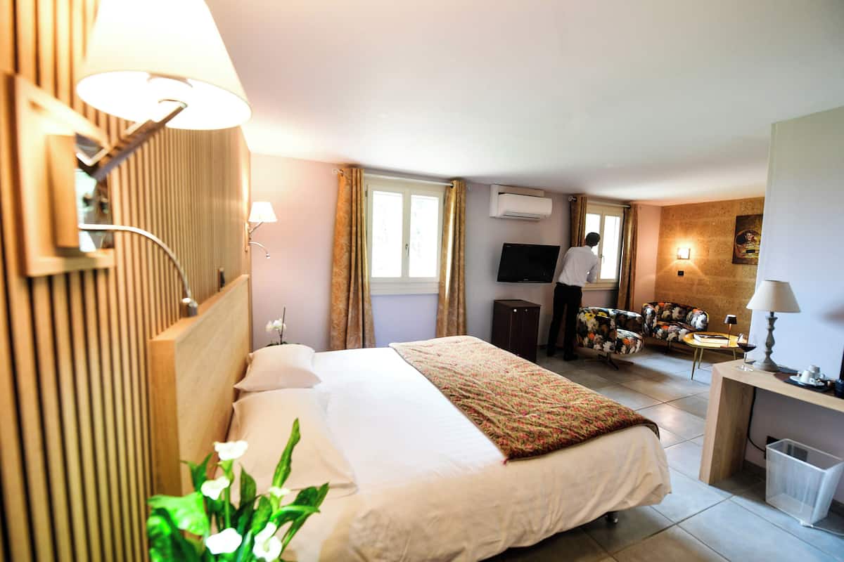 Una habitación de hotel con cama, escritorio, silla, televisión y ventana.